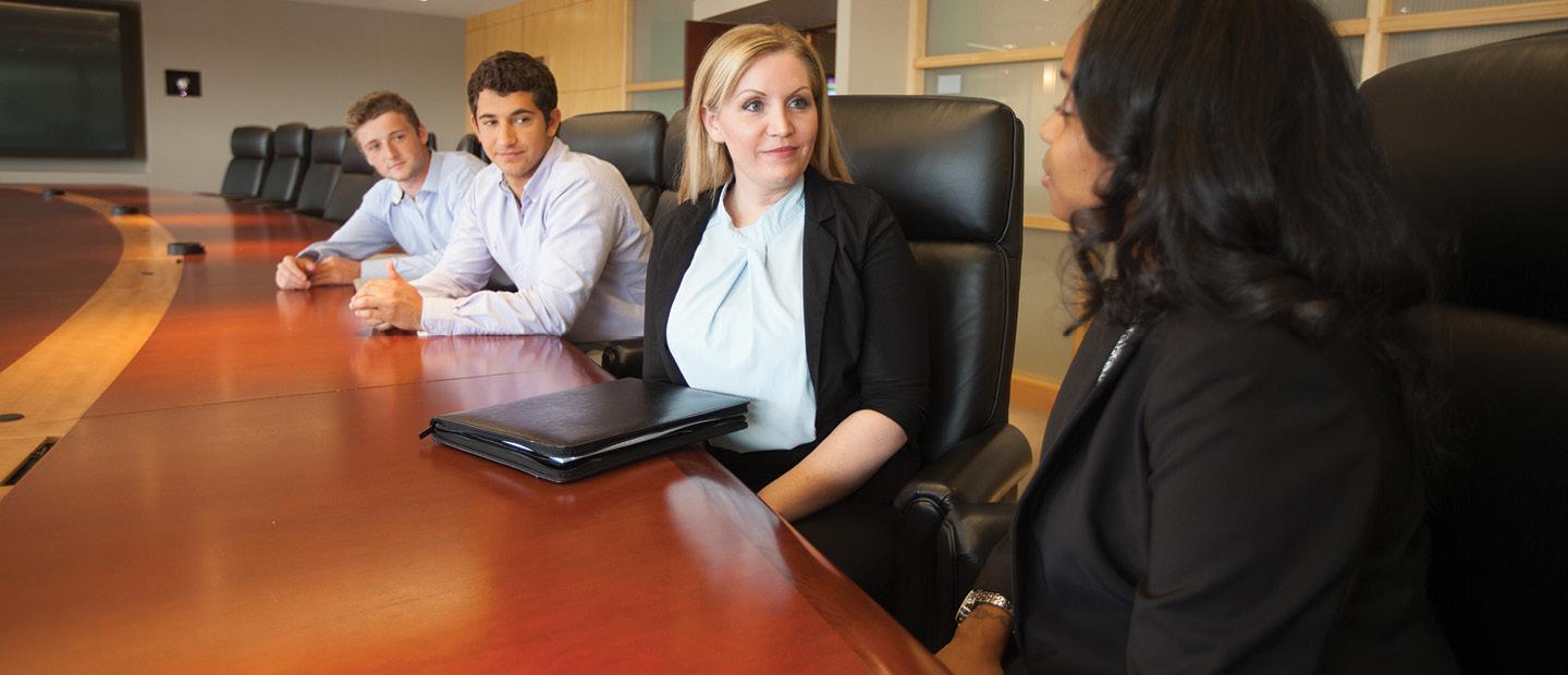 four adults seated in black chairs in a row